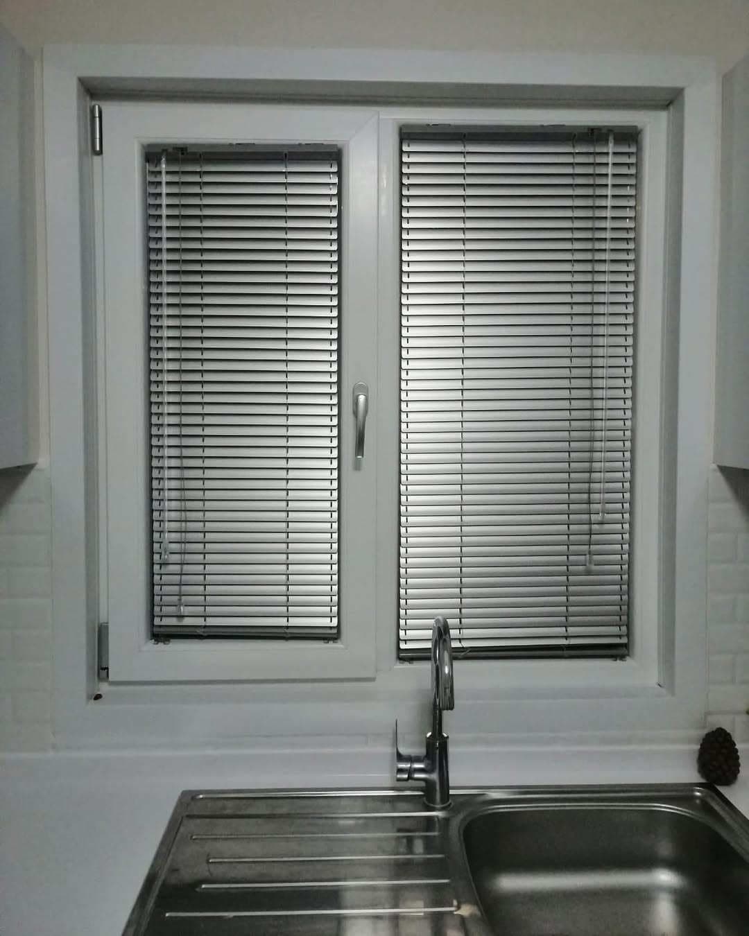 Kitchen sink in front of a window with aluminium Venetian blinds